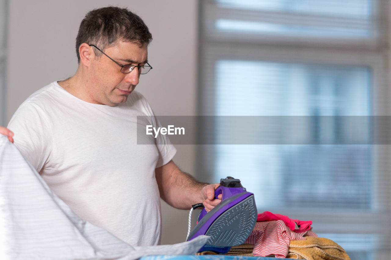 Man ironing cloth at home