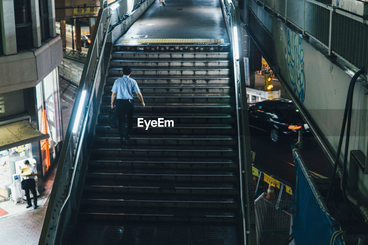 Rear view of man walking on steps