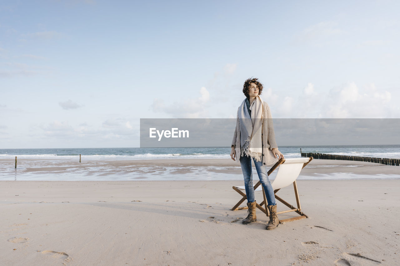 Woman standing next to deckchair on the beach