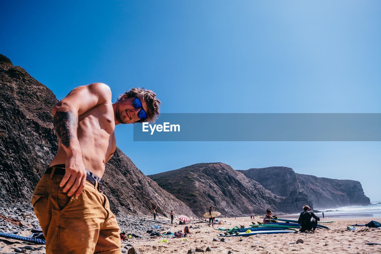 Portrait of shirtless young man standing at beach