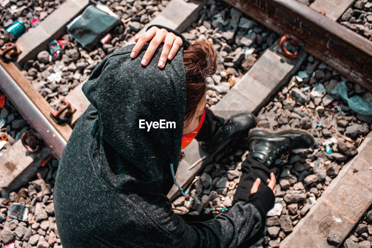 High angle view of woman sitting on railroad tracks