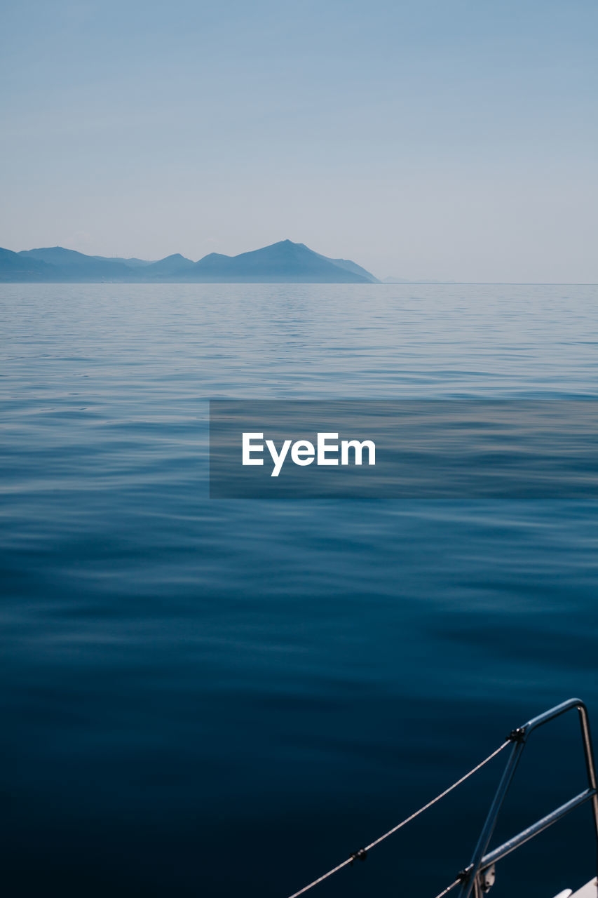 SCENIC VIEW OF SEA AND MOUNTAINS AGAINST CLEAR BLUE SKY