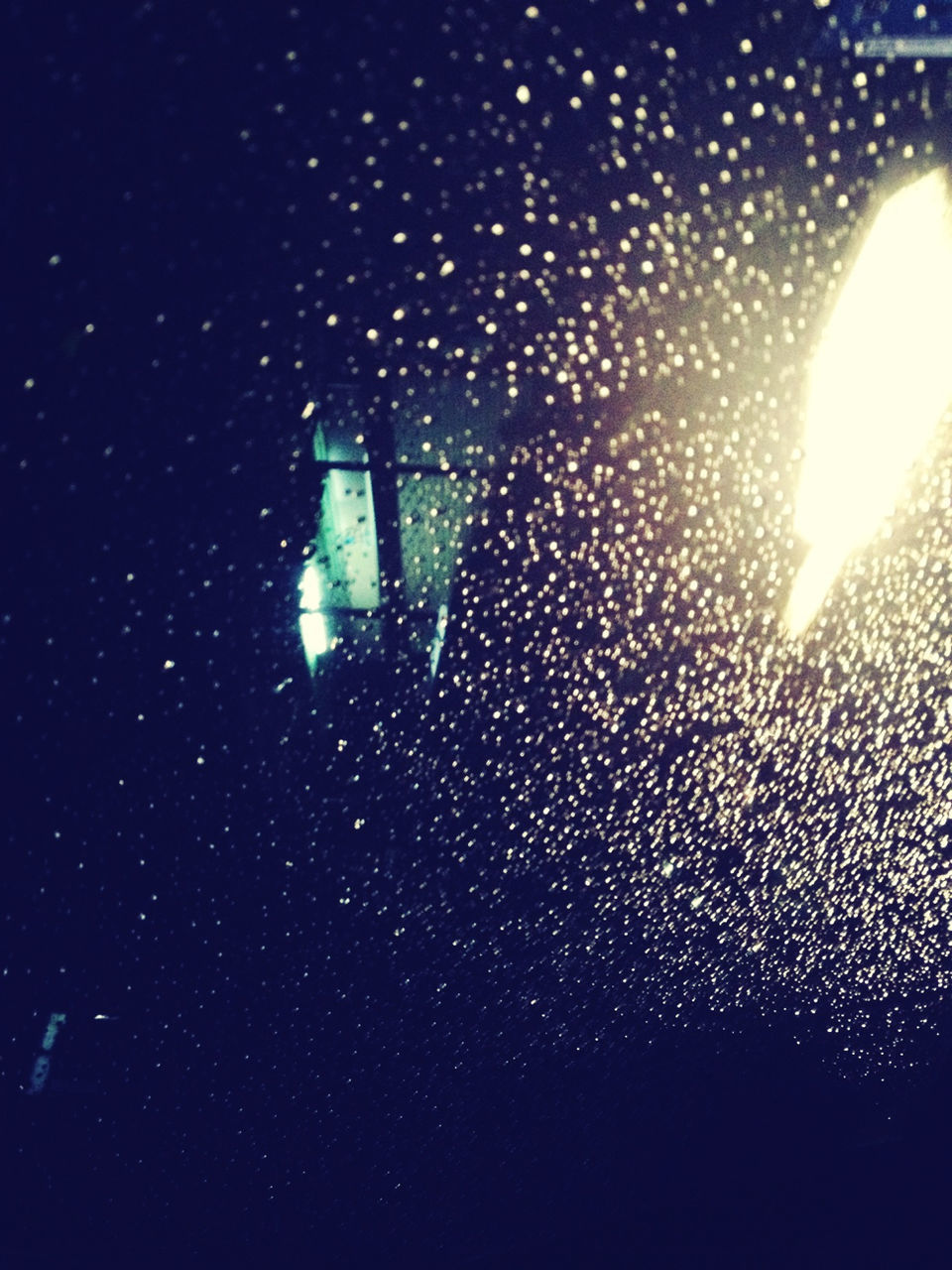Illuminated street light seen through wet glass