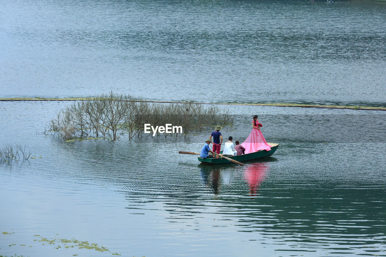 PEOPLE ROWING BOAT ON LAKE AGAINST SKY