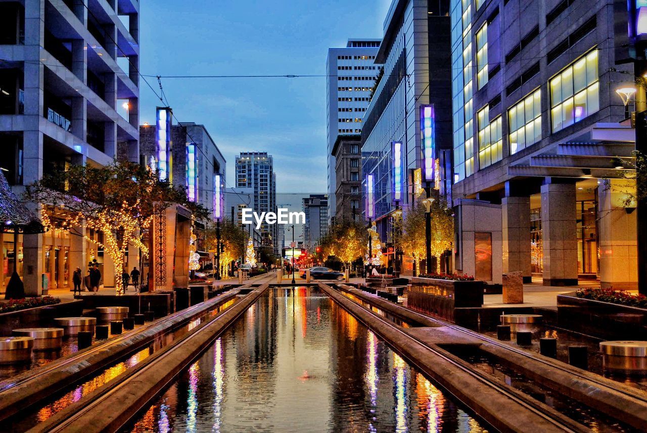 CANAL AMIDST ILLUMINATED BUILDINGS IN CITY