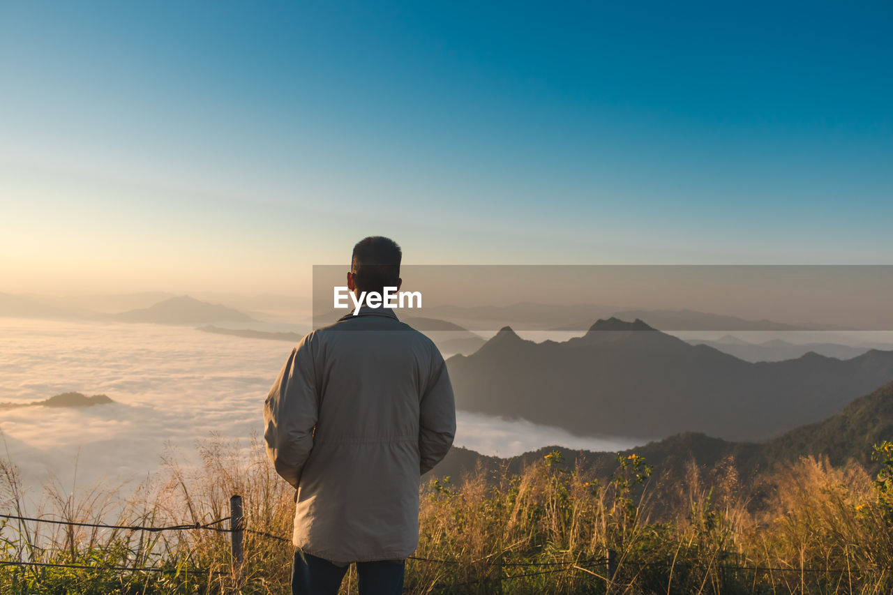Rear view of teenage boy looking at mountains against sky