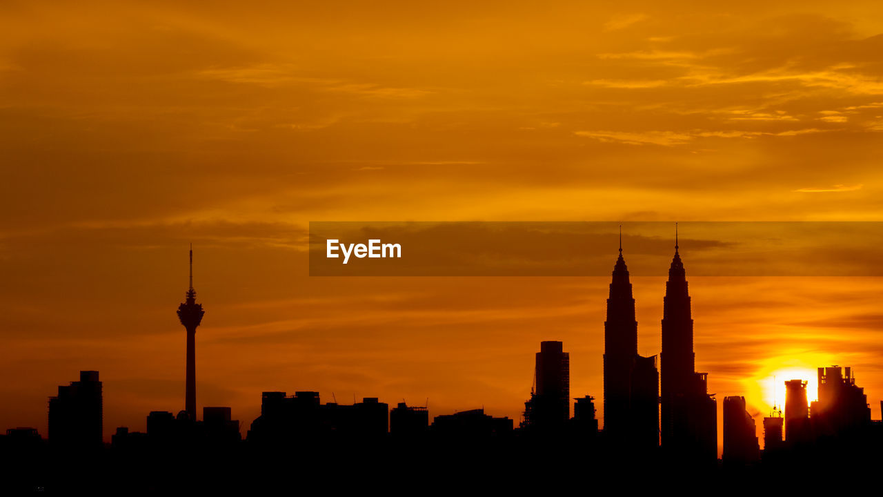 Silhouette of cityscape against orange sky during sunset
