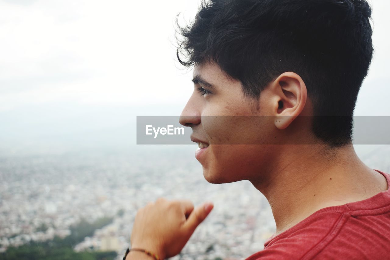 Close-up of young man looking at view against sky