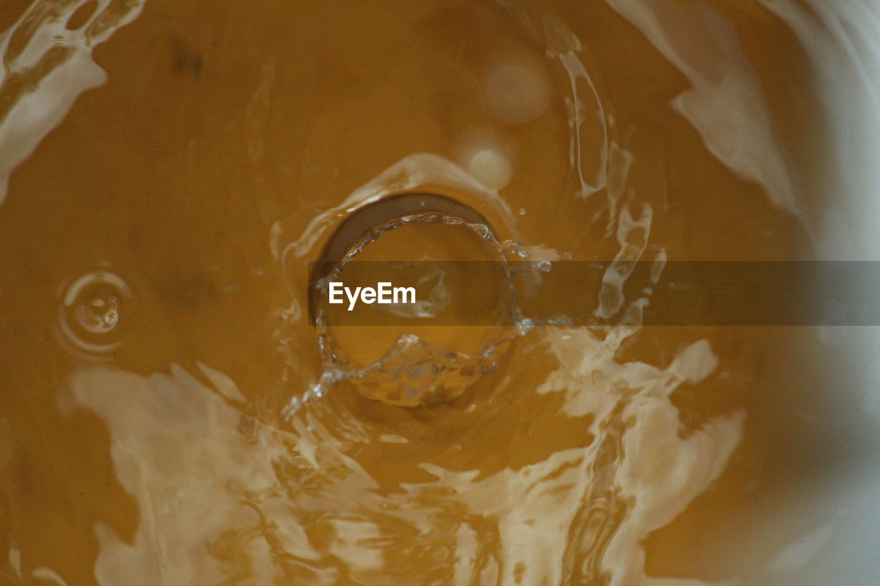 Close-up of water drop splashing into bucket