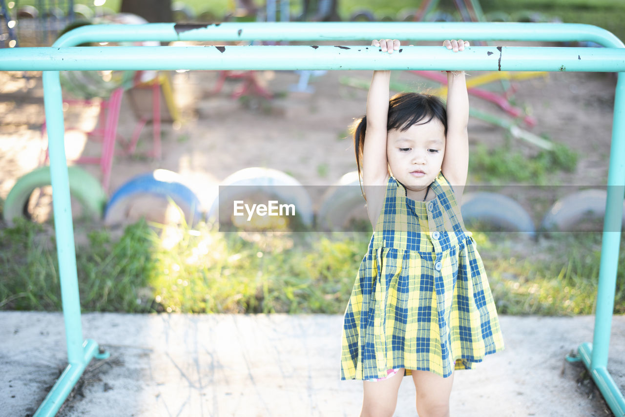 portrait of boy standing on slide at park