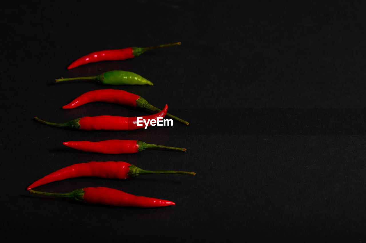 CLOSE-UP OF RED CHILI PEPPERS ON BLACK BACKGROUND