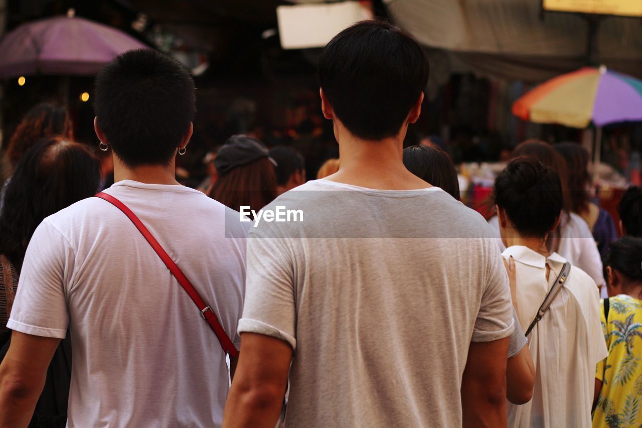 REAR VIEW OF PEOPLE STANDING ON CITY