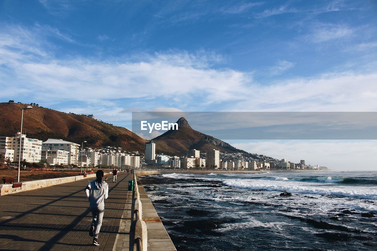 Rear view of woman running on promenade against mountains