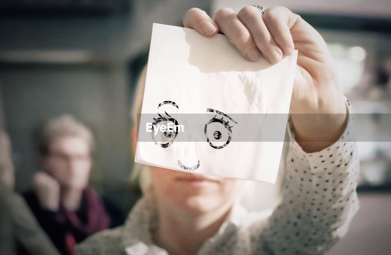 Optical illusion of woman holding anthropomorphic face on tissue