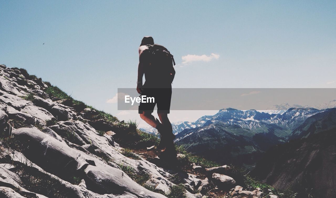 Low angle view of man hiking on mountain against sky