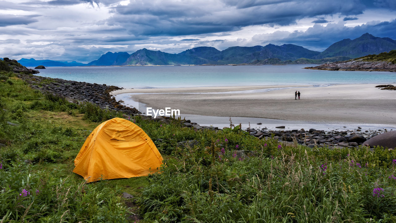 Yellow tent near empty beach with fjords over the horizon
