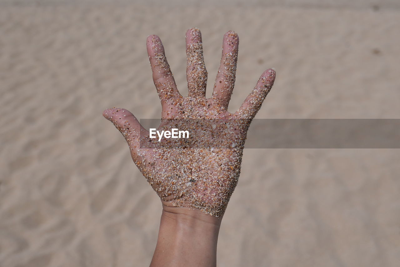 Cropped hand with sand at beach