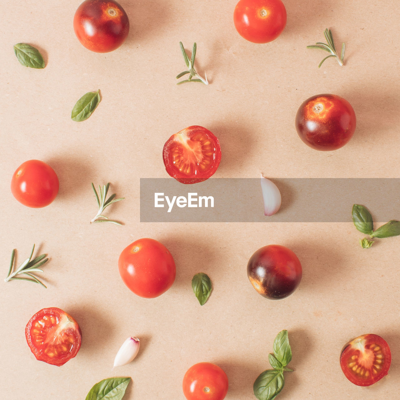 Creative arrangement of cherry tomatoes basil rosemary garlic oregano minimal food concept. flat lay