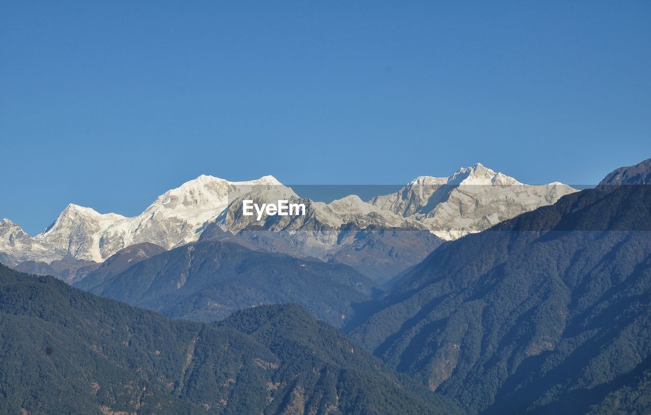 Scenic view of snowcapped mountains against clear blue sky