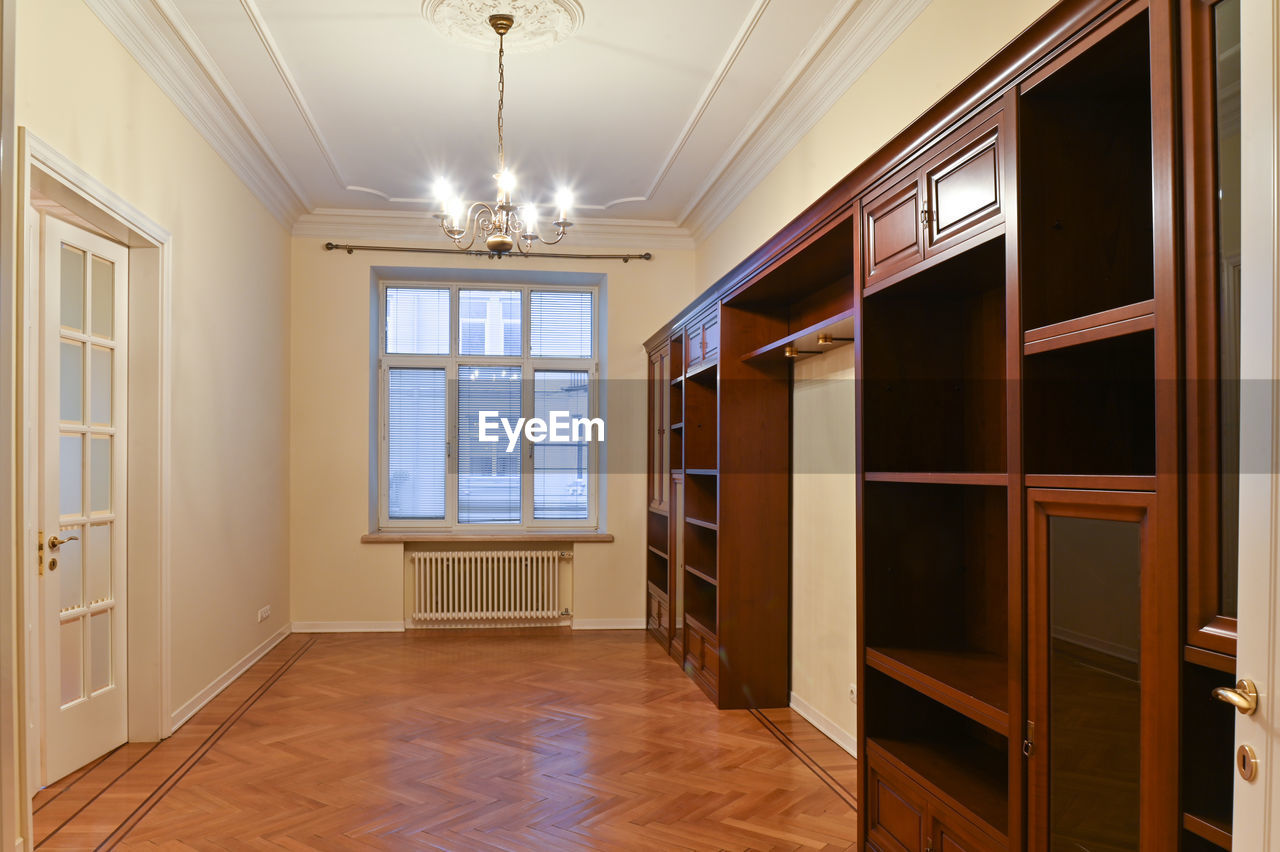 An empty room with a large window, rent, sale and furniture made of natural wood.