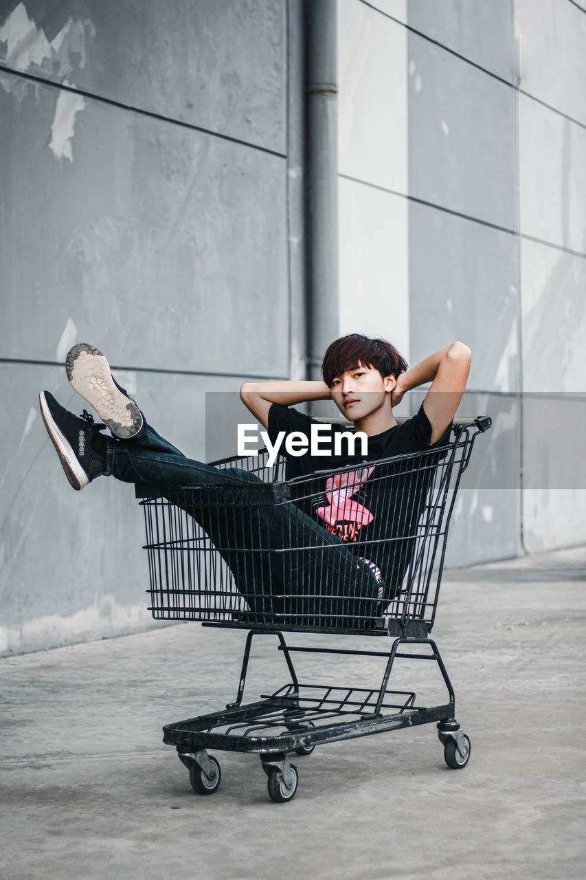 FULL LENGTH OF BOY SITTING ON WALL