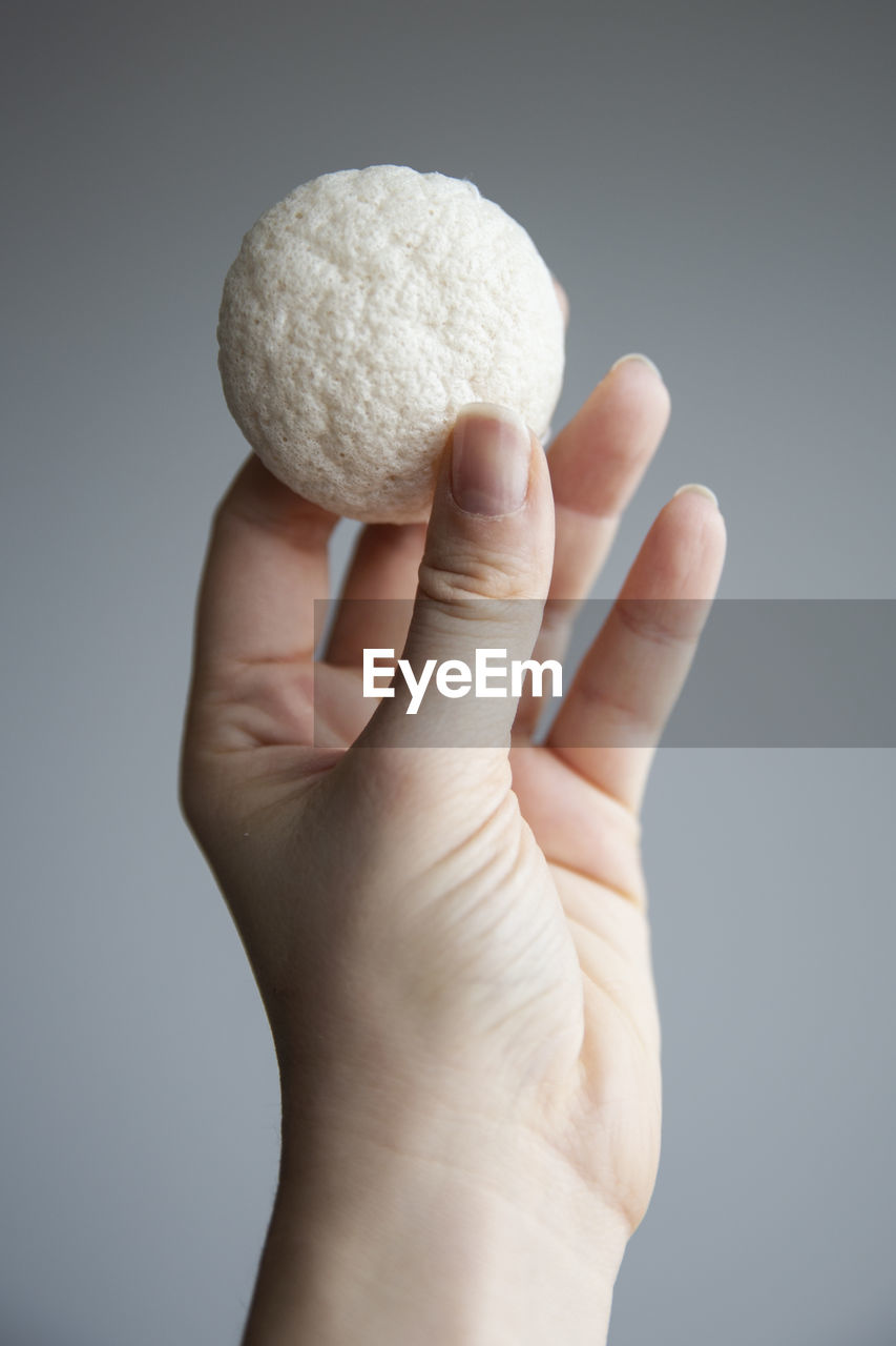 Close-up of hand holding apple against white background