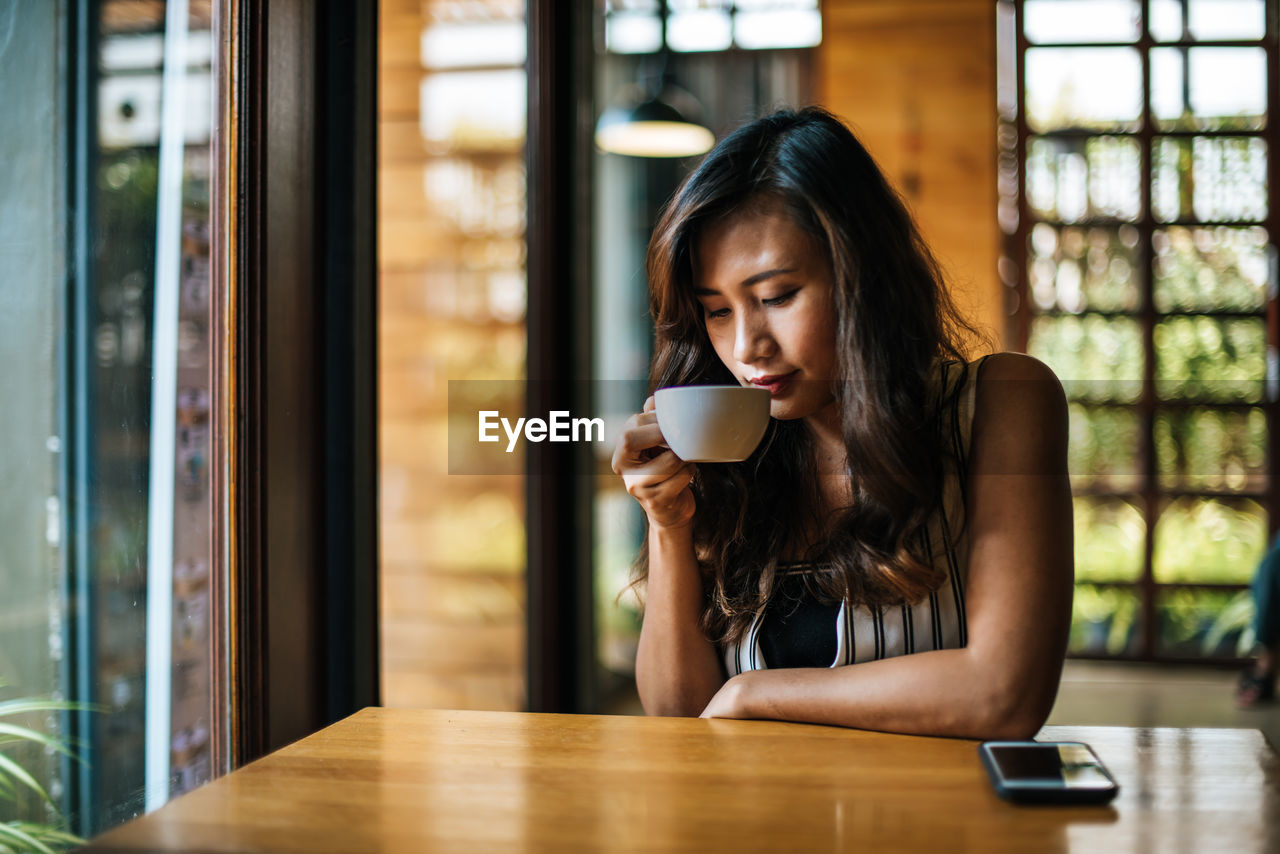 YOUNG WOMAN DRINKING COFFEE IN CUP