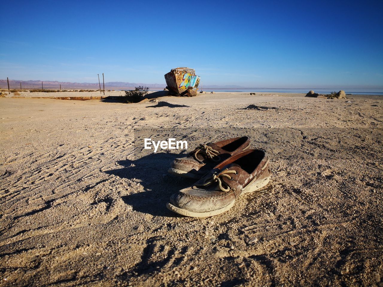 Abandoned shoes on sandy beach against clear sky