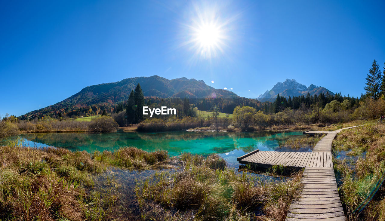 Scenic view of lake and mountains against clear blue sky