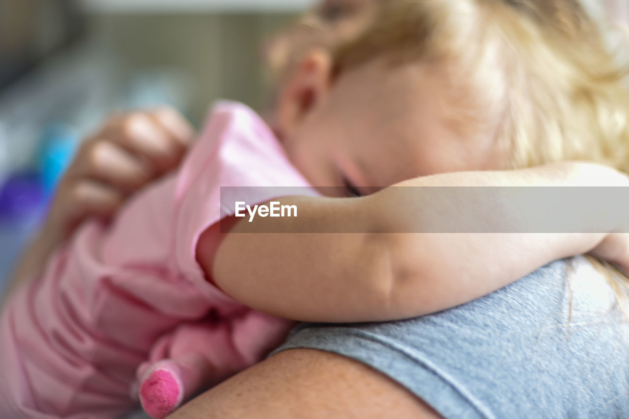 Midsection of woman embracing daughter at home