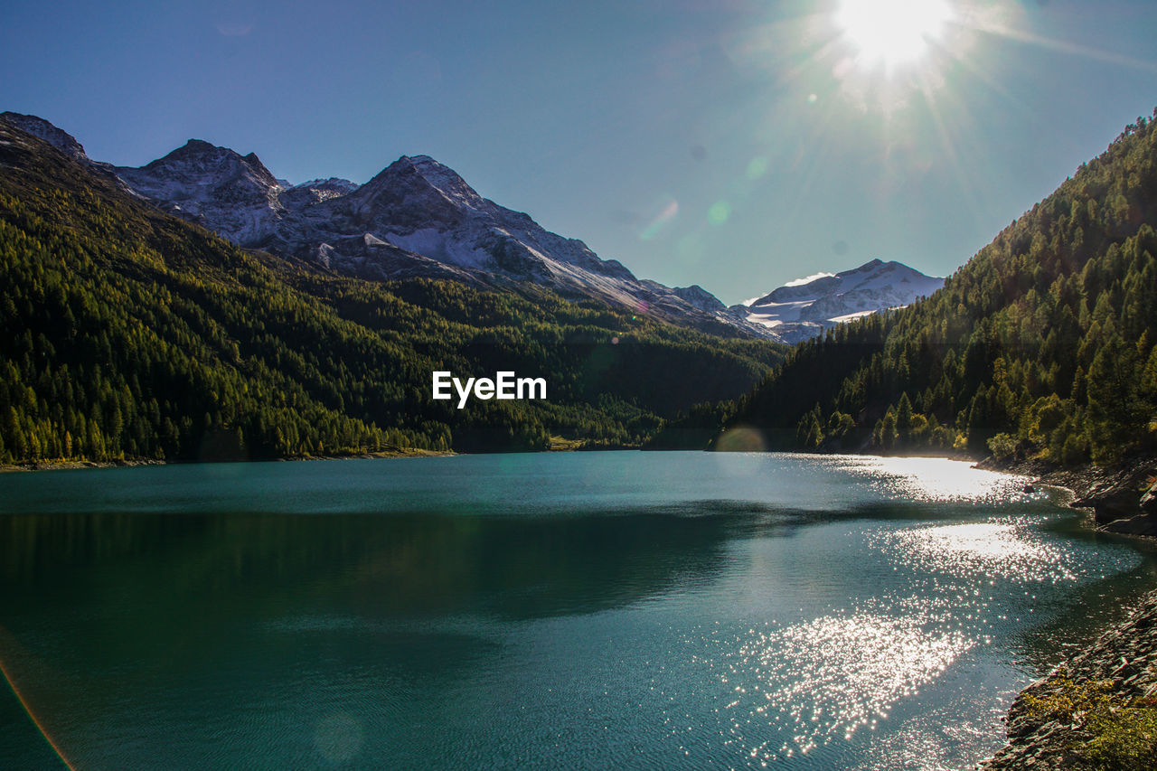 SCENIC VIEW OF LAKE AND MOUNTAINS AGAINST BRIGHT SKY