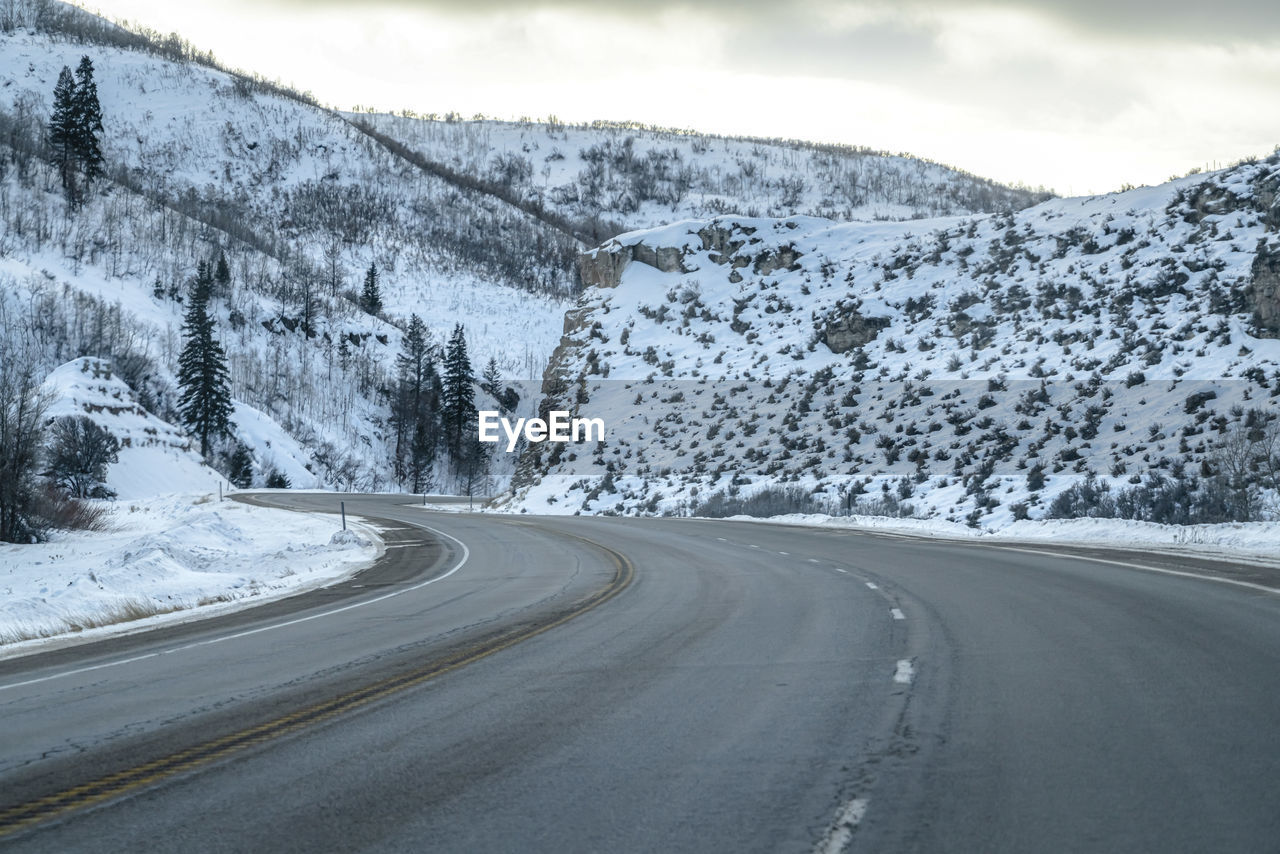 ROAD BY SNOWCAPPED MOUNTAIN AGAINST SKY