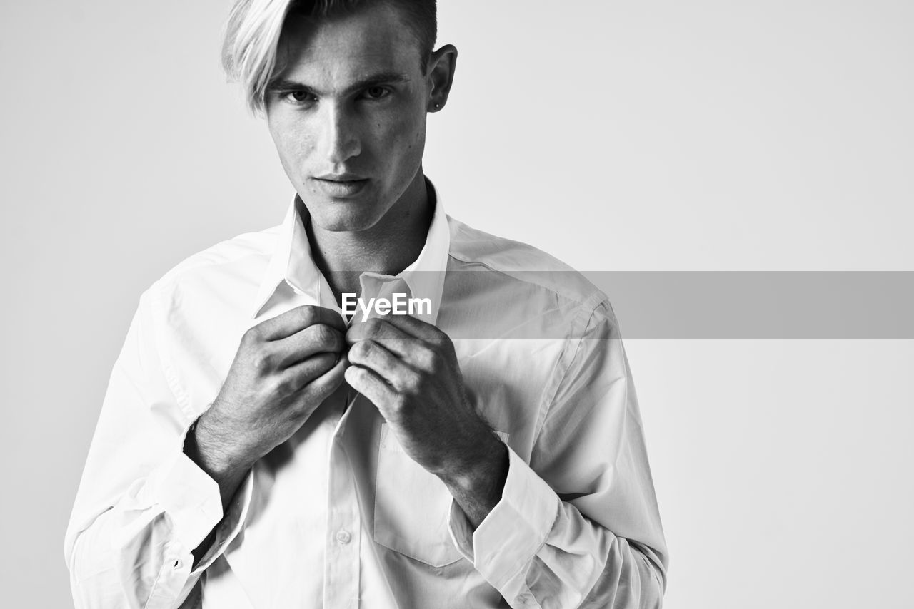 Portrait of young man standing against white background