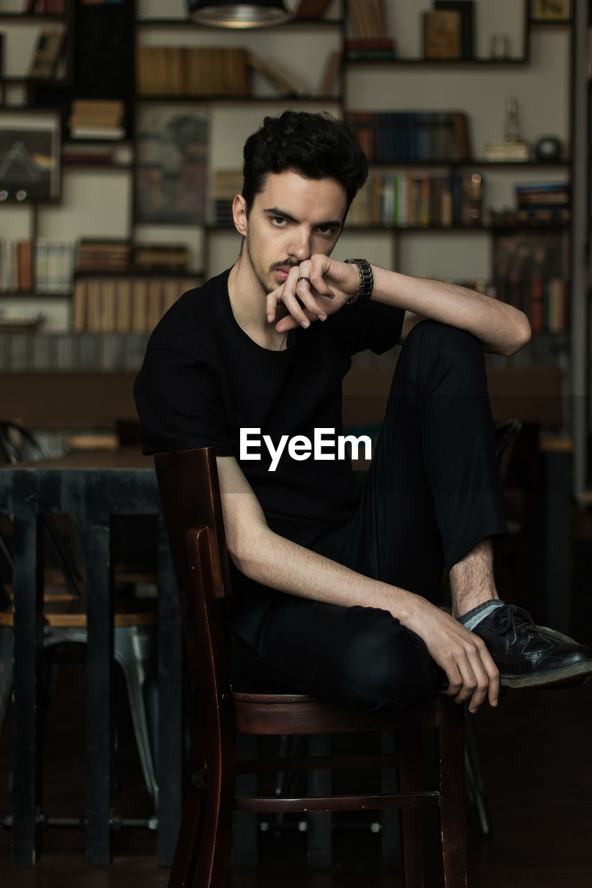 YOUNG MAN SITTING ON CHAIR IN OFFICE