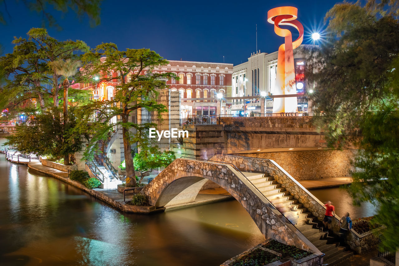 ARCH BRIDGE OVER RIVER AMIDST BUILDINGS