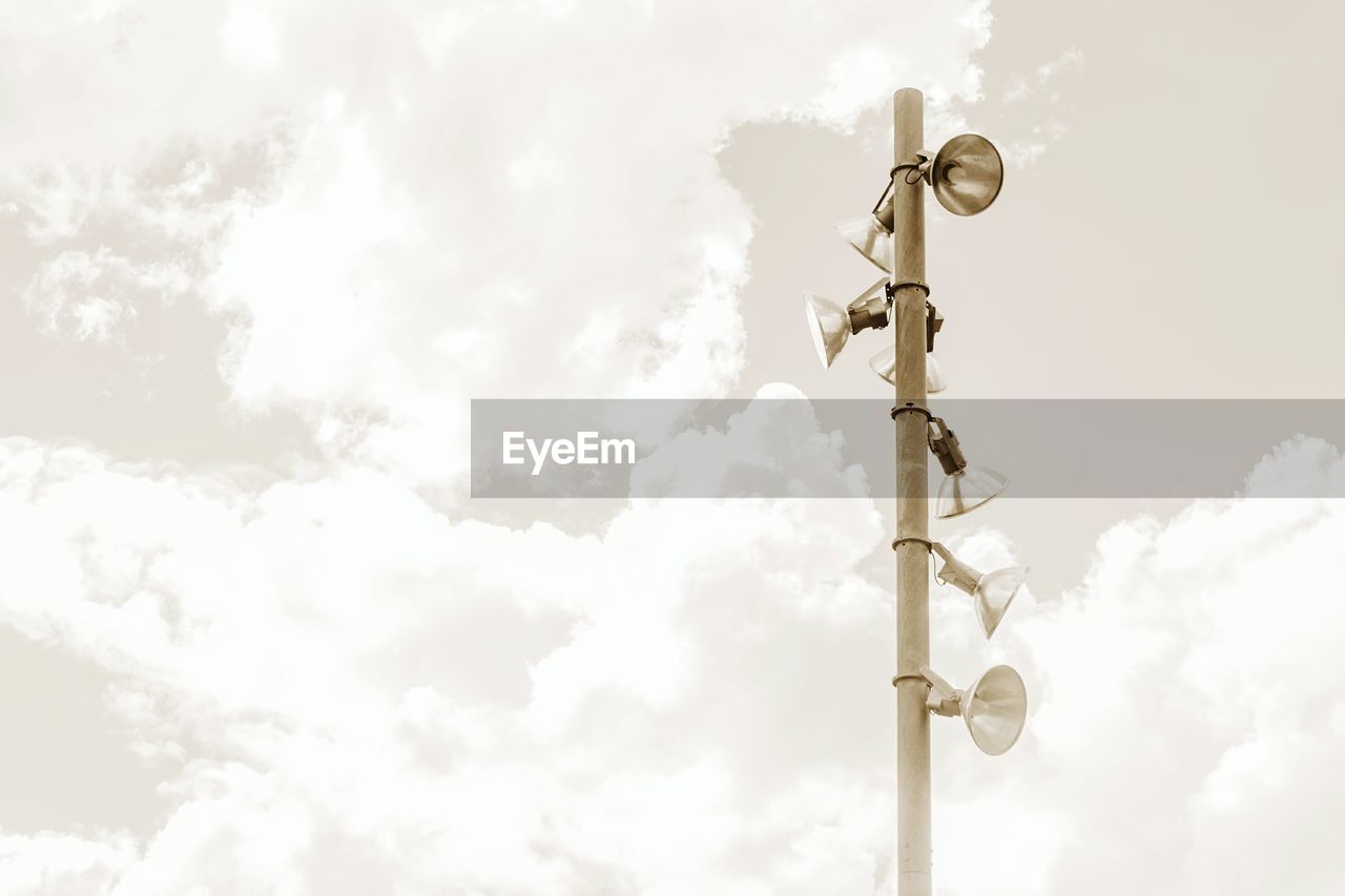 Low angle view of lighting equipment on pole against cloudy sky