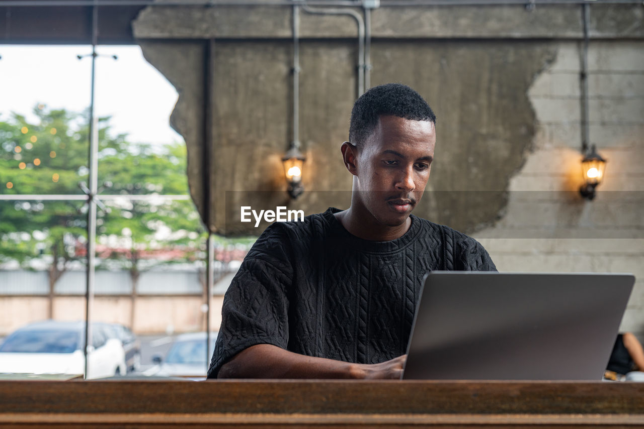 portrait of man using laptop while sitting on table