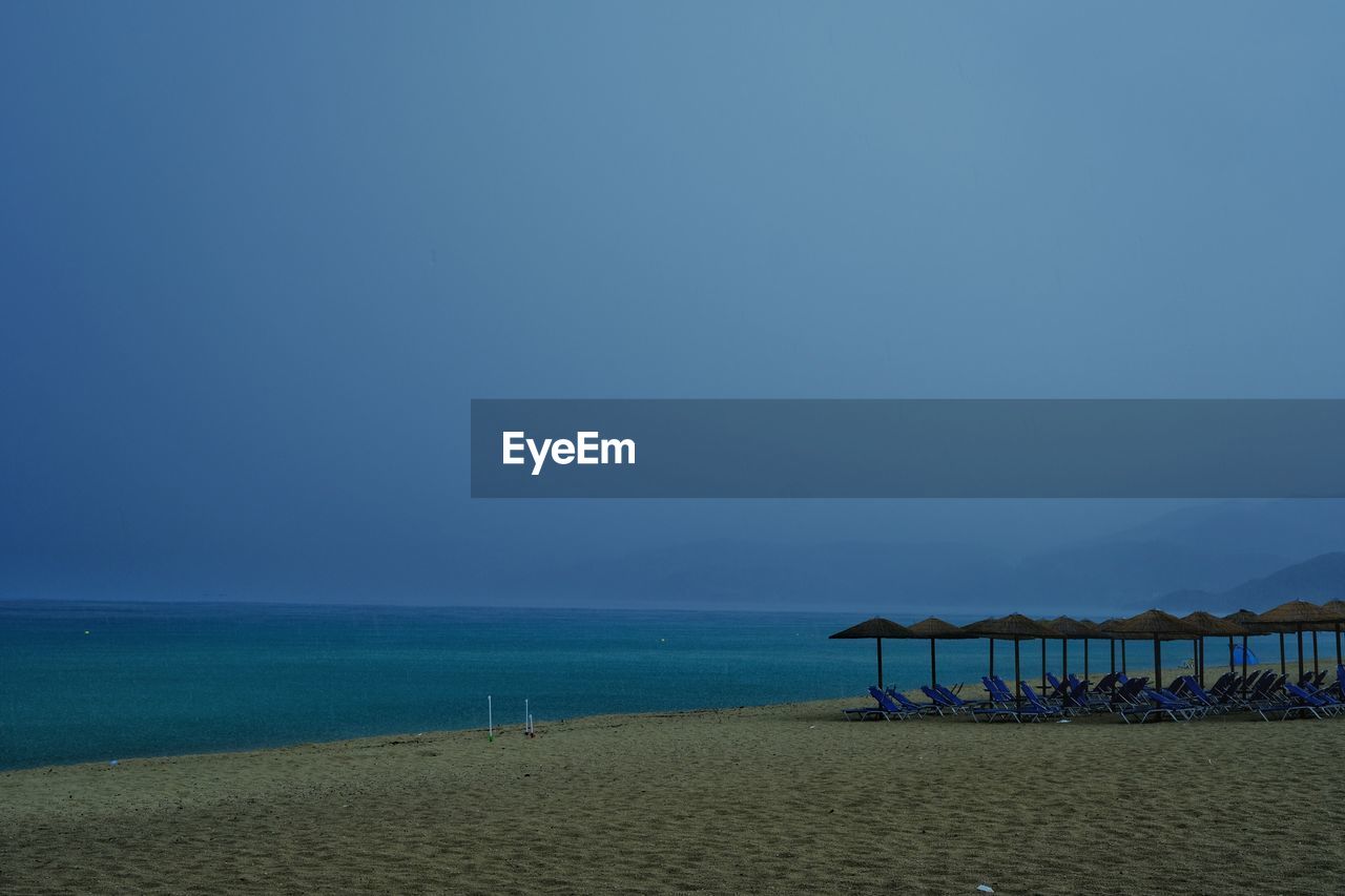 water, sea, beach, land, horizon, sky, ocean, body of water, scenics - nature, beauty in nature, sand, nature, tranquility, horizon over water, tranquil scene, blue, coast, shore, travel destinations, holiday, vacation, trip, no people, travel, clear sky, copy space, tourism, hut, idyllic, wave, bay, outdoors, dusk, architecture, coastline, day, chair, summer, environment, seascape, non-urban scene, cloud, built structure