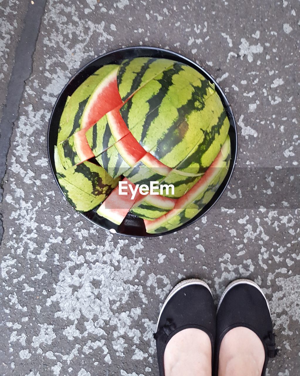 Low section of person standing next to melon