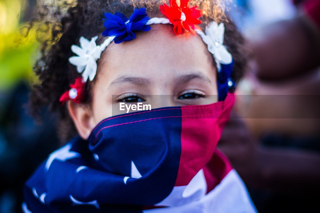 Close-up portrait of girl covering mouth with american flag