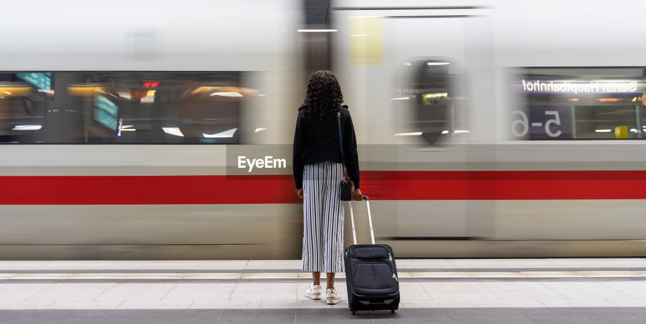 Rear view of woman standing against moving train 