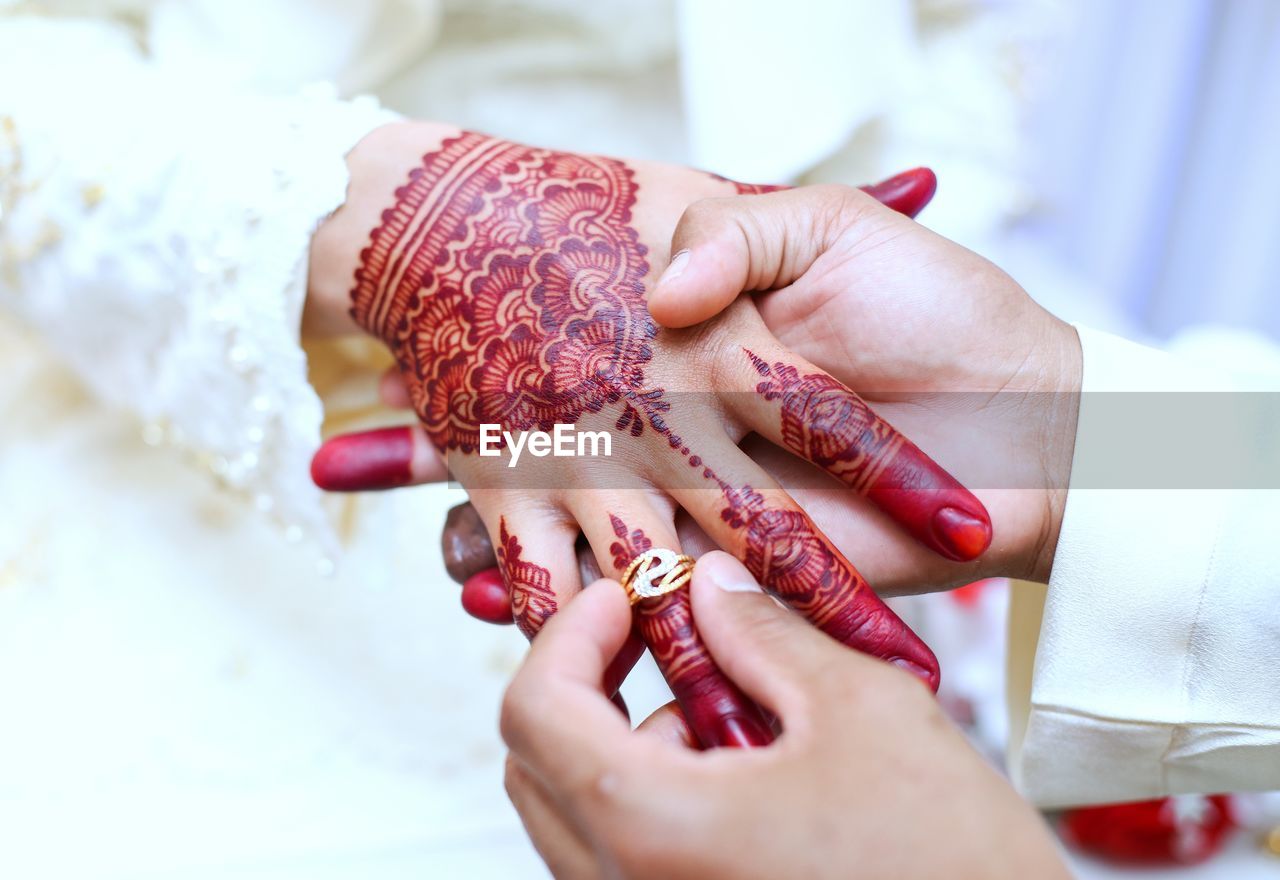 Cropped image of groom inserting wedding ring in bride finger during ceremony