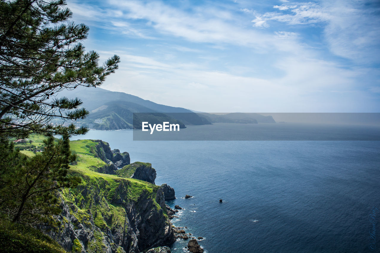 Scenic view of mountains by river against cloudy sky