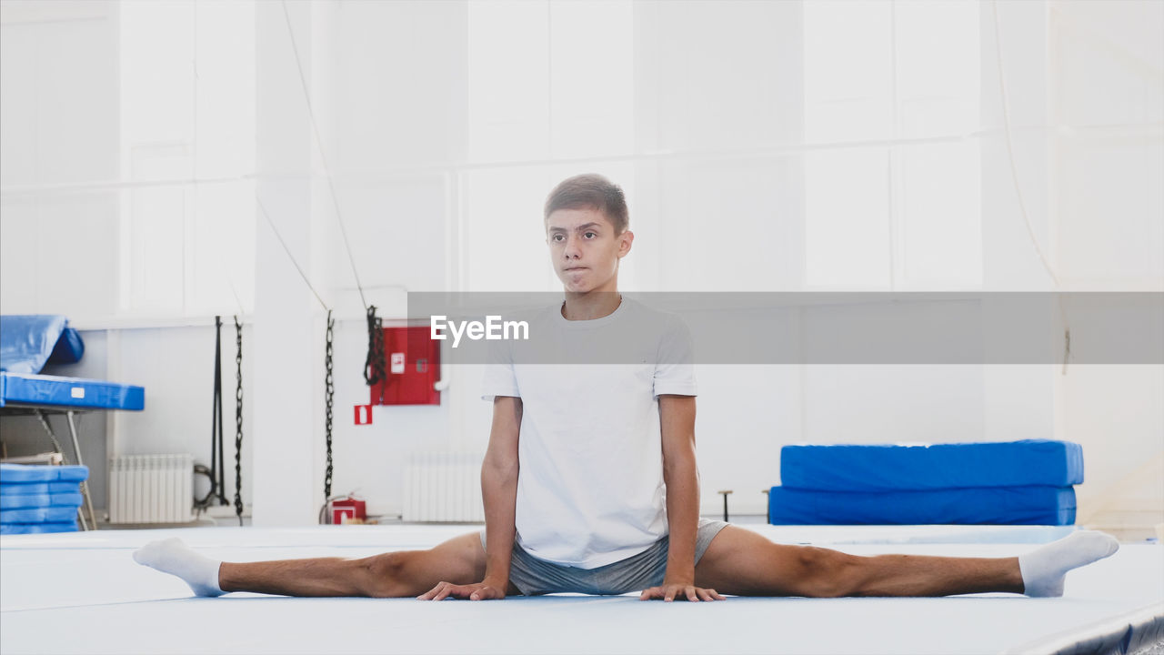 Full length of teenager boy stretching at home