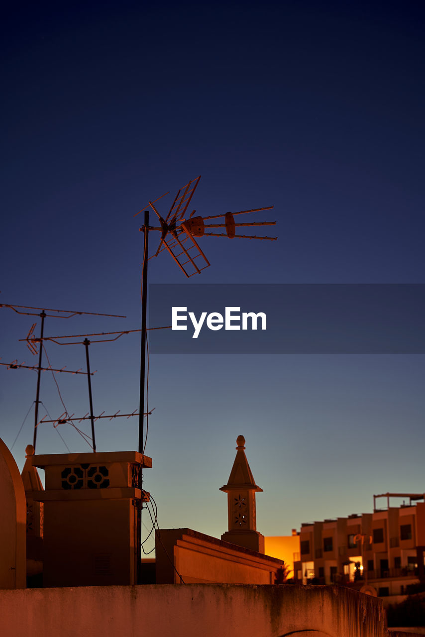 Antennas on a rooftop in the golden light of nightfall