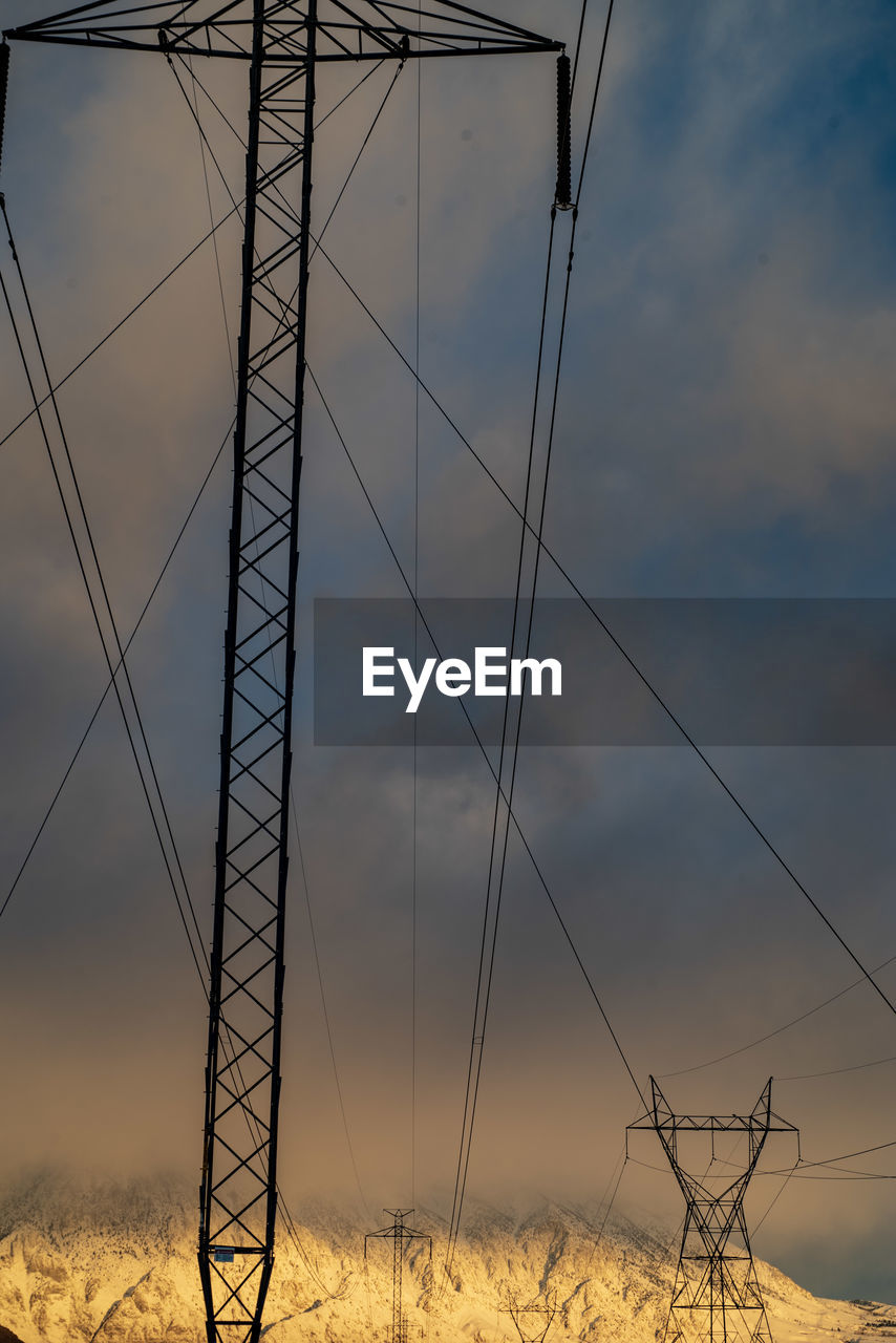 Low angle view of electricity pylon on field against sky