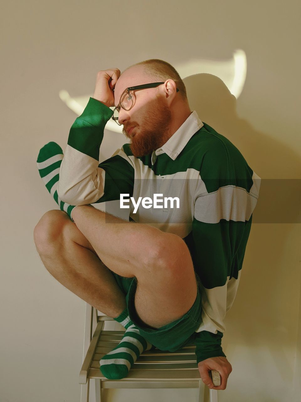 Side view of man sitting on chair against wall