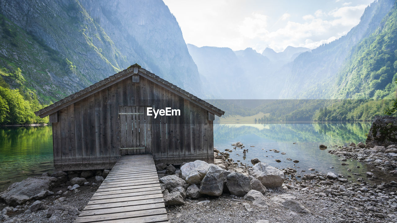 Old wooden boathouse with boardwalk with pristine alpine lake and mountains in background, obersee
