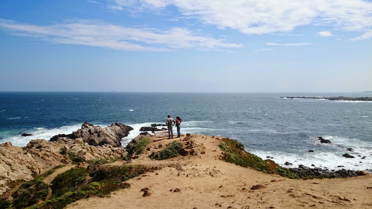 Rear view of man and woman standing at sea shore