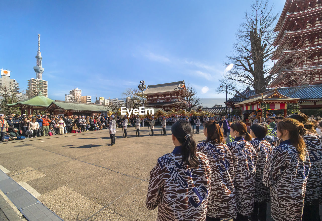 GROUP OF PEOPLE WALKING IN FRONT OF BUILDING